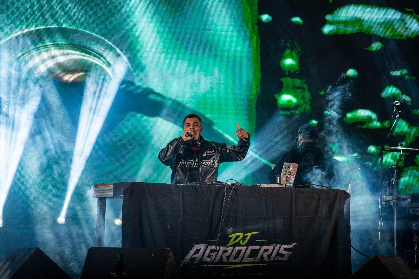 DJ AGROCRIS no palco com iluminação verde e fumaça