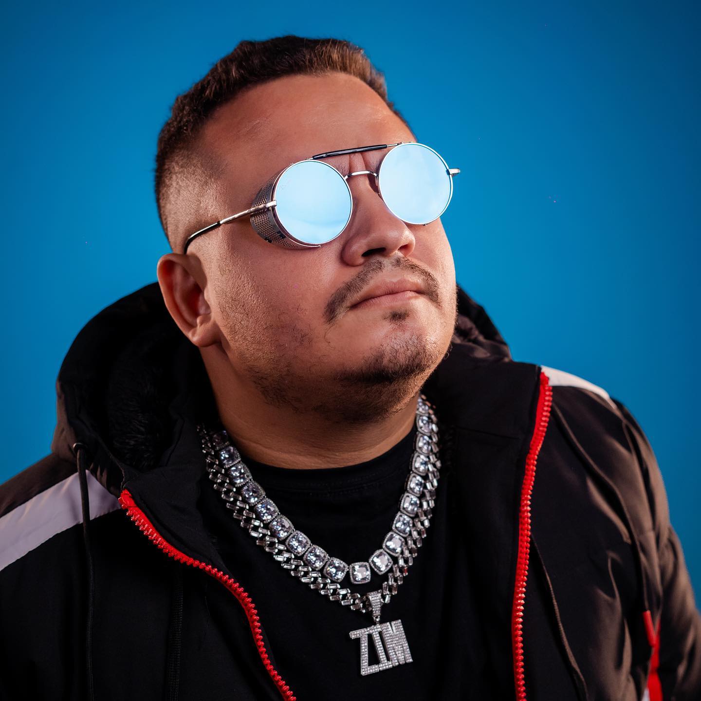 Retrato do DJZIM com óculos em fundo azul